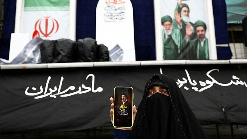 אישה ב טהרן איראן מציגה צילום של מוג'תבא חמינאי 26.3.26 מלחמה עם איראן