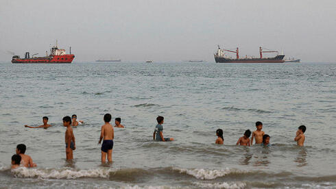Iranian children on the beach of Bandar Abbas against the backdrop of tankers stranded in the Strait of Hormuz Iranian children on the beach of Bandar Abbas against the backdrop of tankers stranded in the Strait of Hormuz