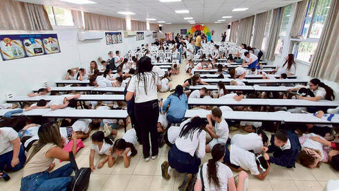 Students in Kiryat Shmona take cover during a missile alarm. 