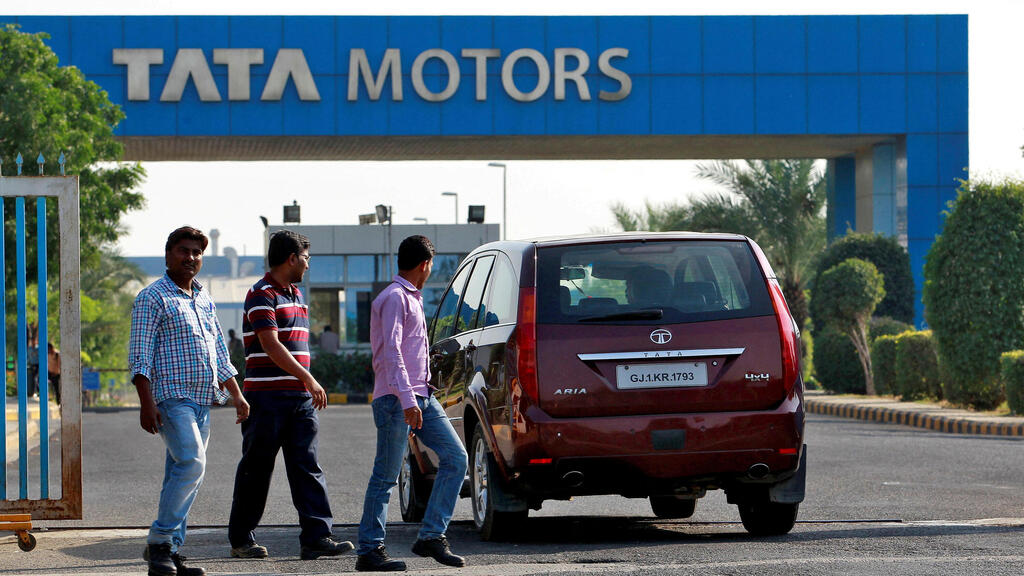 מפעל של טאטא מוטורס (צילום: REUTERS) FILE PHOTO: FILE PHOTO: A vehicle drives past three men walking out of a Tata Motors car plant at Sanand in the western Indian state of Gujarat, India, October 27, 2016. REUTERS/Amit Dave/File Photo/File Photo