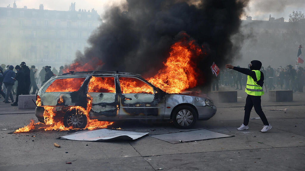 מפגין ליד רכב בוער בפריז (צילום: Abdul Saboor/Reuters) מפגין ליד רכב בוער ב פריז צרפת