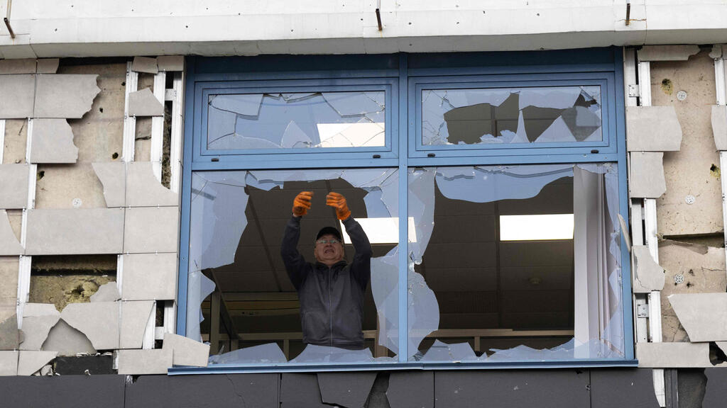 A man looks at a broken window in an office building damaged following an air attack in Kyiv on October 22, 2026, amid the Russian invasion of Ukraine. (Photo by Serhii Okunev / AFP) 