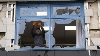 A man looks at a broken window in an office building damaged following an air attack in Kyiv on October 22, 2026, amid the Russian invasion of Ukraine. (Photo by Serhii Okunev / AFP) 